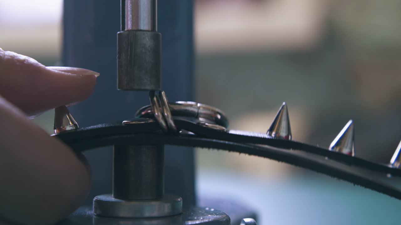 디자이너는 검은색 가죽 목걸이에 금속 액세서리를 설정합니다.