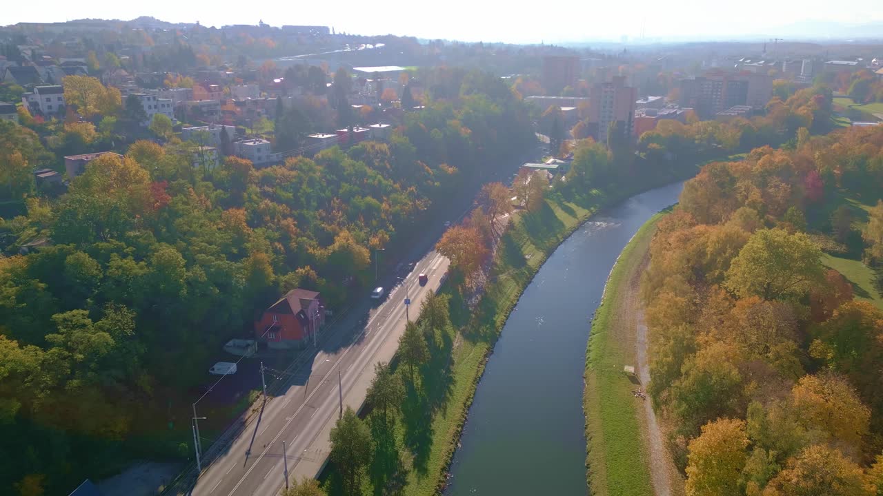 Drone reveals River Ostravice with Autumnal Komensy park and cityscape
