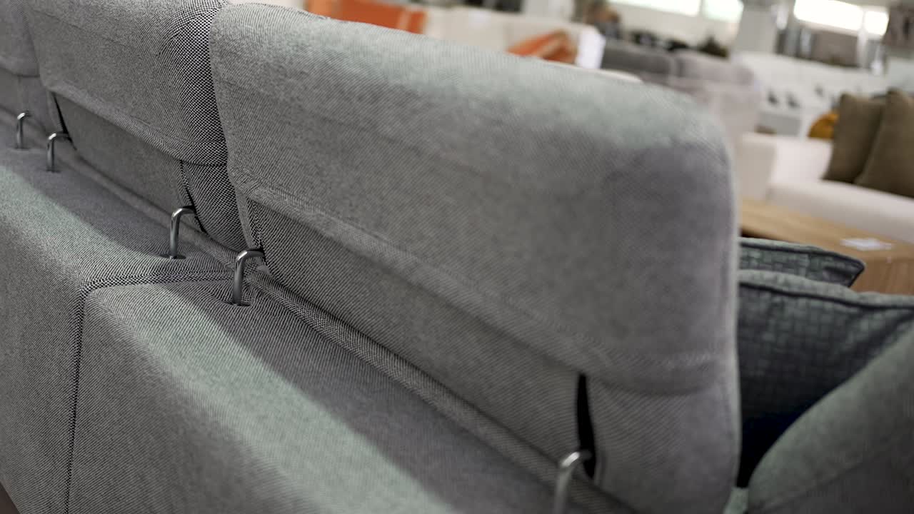Close-up look at a stylish gray sofa in a furniture showroom. The video highlights the clean lines, fabric texture, and overall design of the seat, perfect for contemporary homes