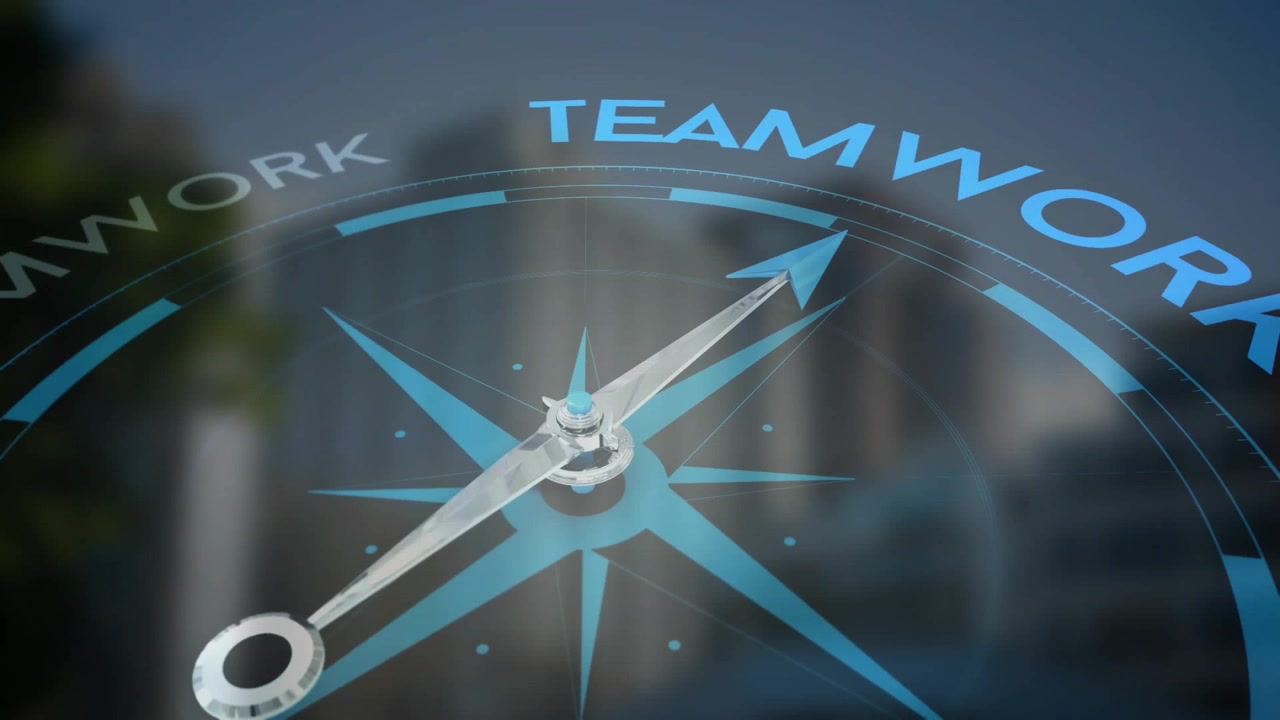 Rotating compass needle shifting toward rim labeled TEAMWORK at city skyline, showing lens flare