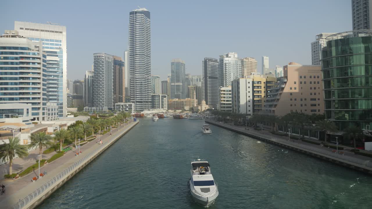 A serene canal in Dubai framed by modern skyscrapers, yachts, and palm trees