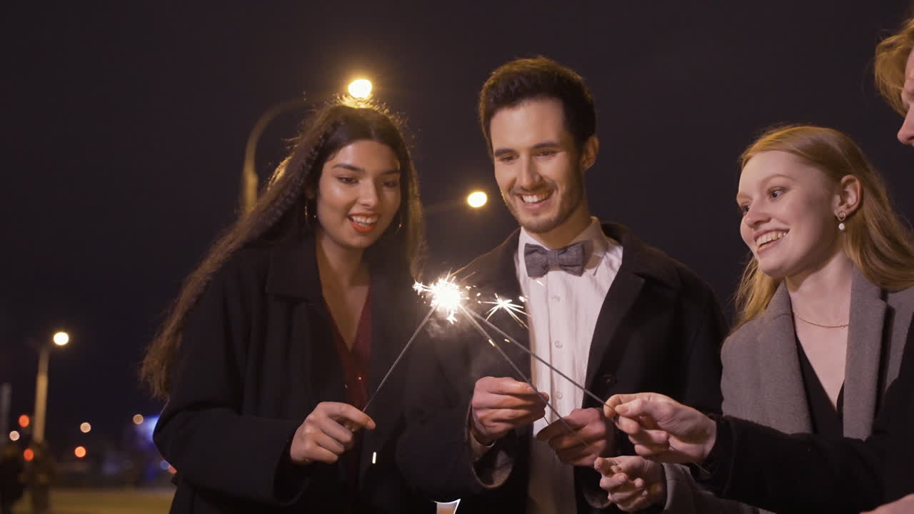 Group Of Friends Wearing Elegant Clothes Lighting Sparklers In The Street After The New Year's Party