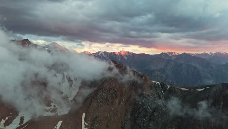 drone view of the mountains in kazakhstan during golden hour with clouds and sunlit peaks