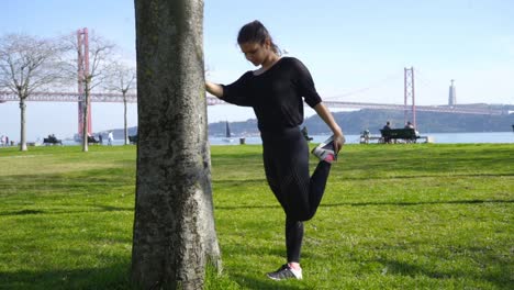 mujer joven deportiva concentrada estirándose en el parque