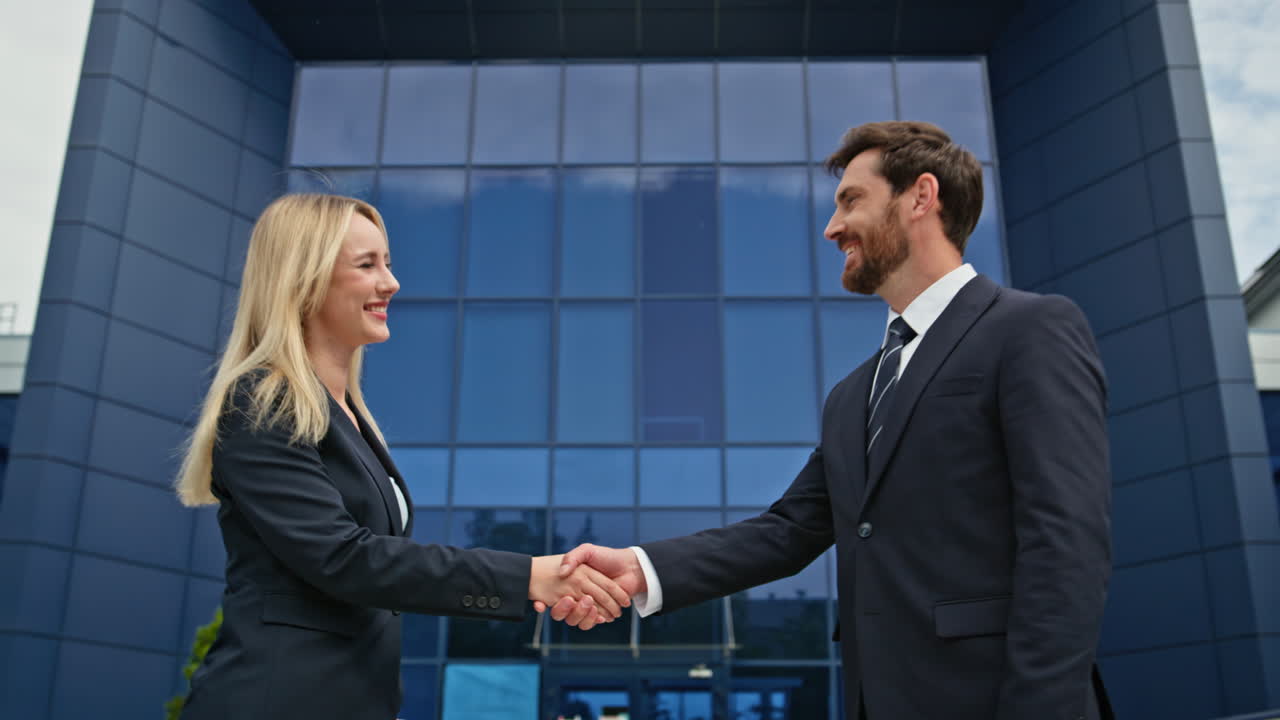 Closeup business people handshake in front modern office building outdoors