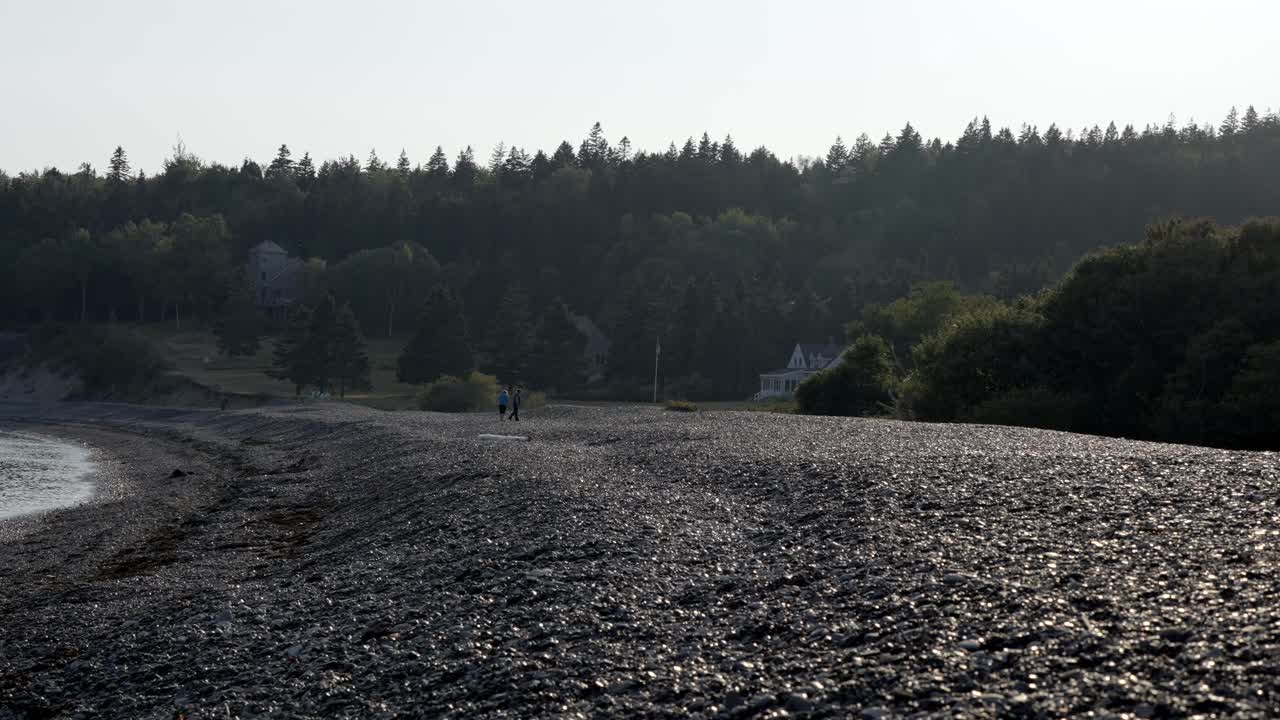 Slow motion footage of people strolling along a tranquil and rocky coastline