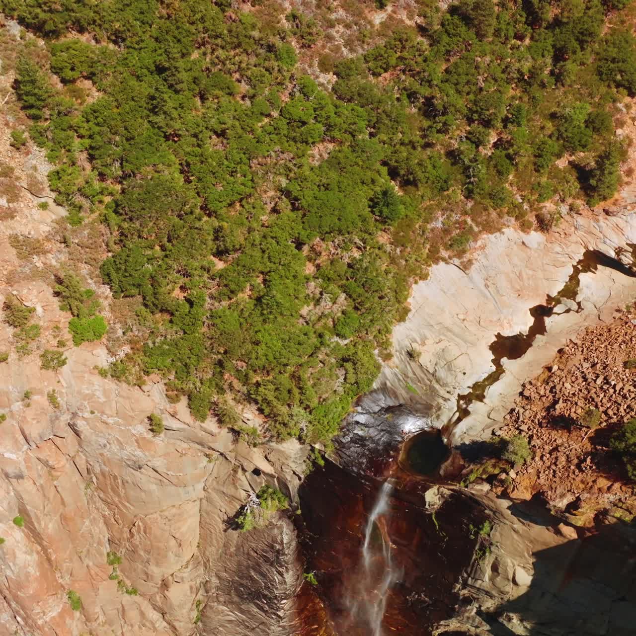 Tiny waterfall in the mountains of Yosemite, California, USA. High rock cliff with a creek falling down. Sunny day footage from top