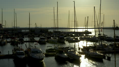 Sonnenuntergang-über-Dem-Jachthafen-Mit-Silhouettierten-Booten-Und-Vor-Anker-Liegenden-Yachten