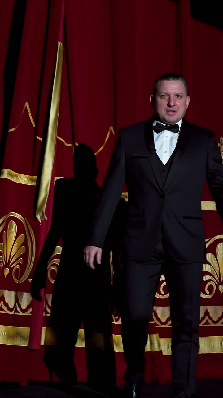 Man is speaking in the light of the floodlights standing on stage to the camera. Actor, artist on performance. Active gestures with hands. Vertical video