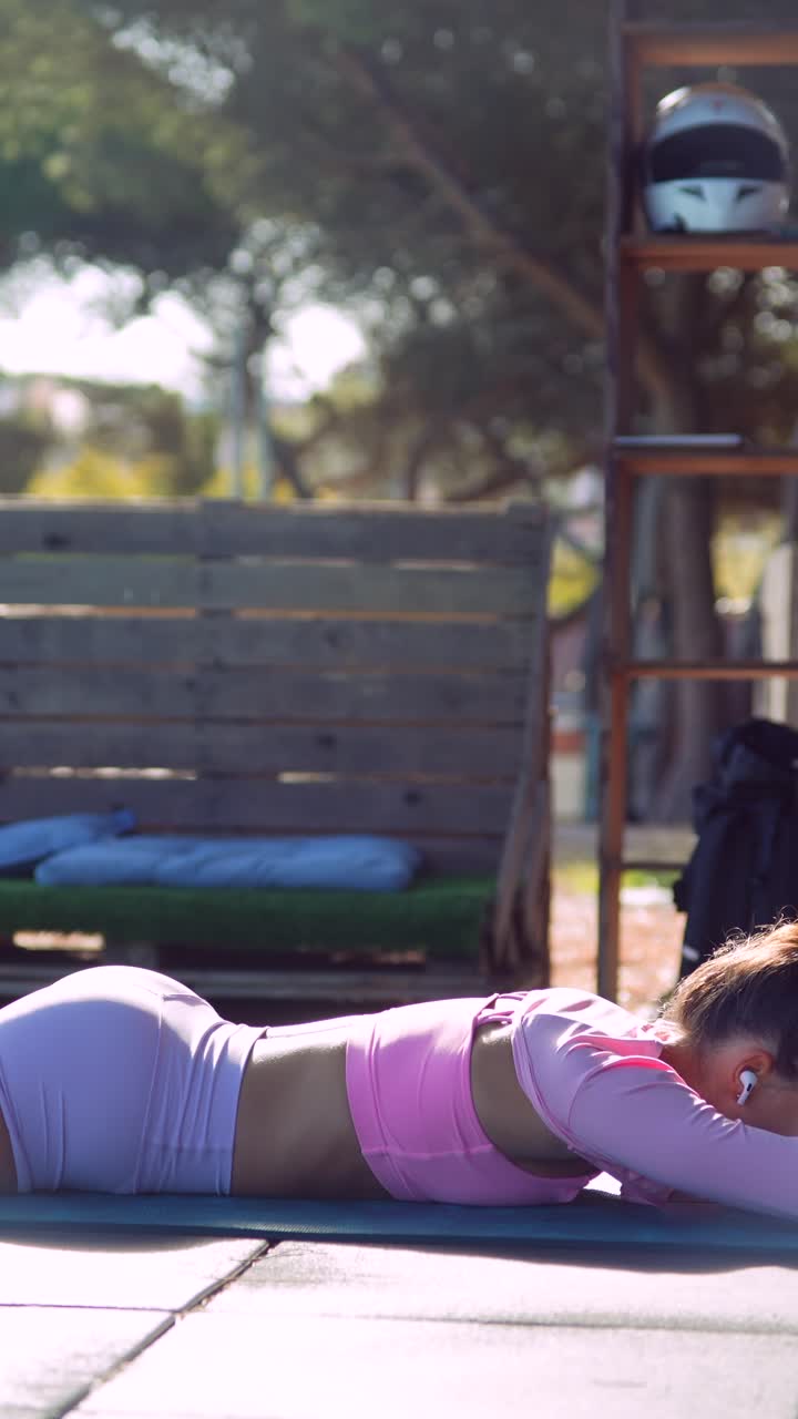 Donna in forma che esegue estensioni della schiena su un tappetino durante un allenamento all'aperto