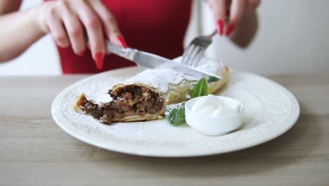 unrecognizable girl in red dress taking desert strudel at the restaurant using fork and knife. slow motion shot