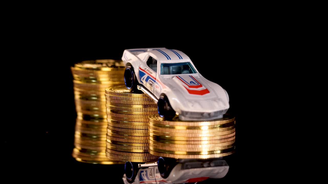 White toy car rotates atop gold coin stacks, black reflective background, dramatic studio lighting