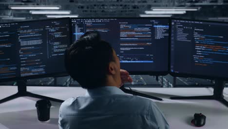 programador trabajando en múltiples monitores en la sala de servidores