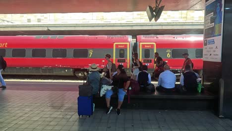 people seated with luggage at train platform