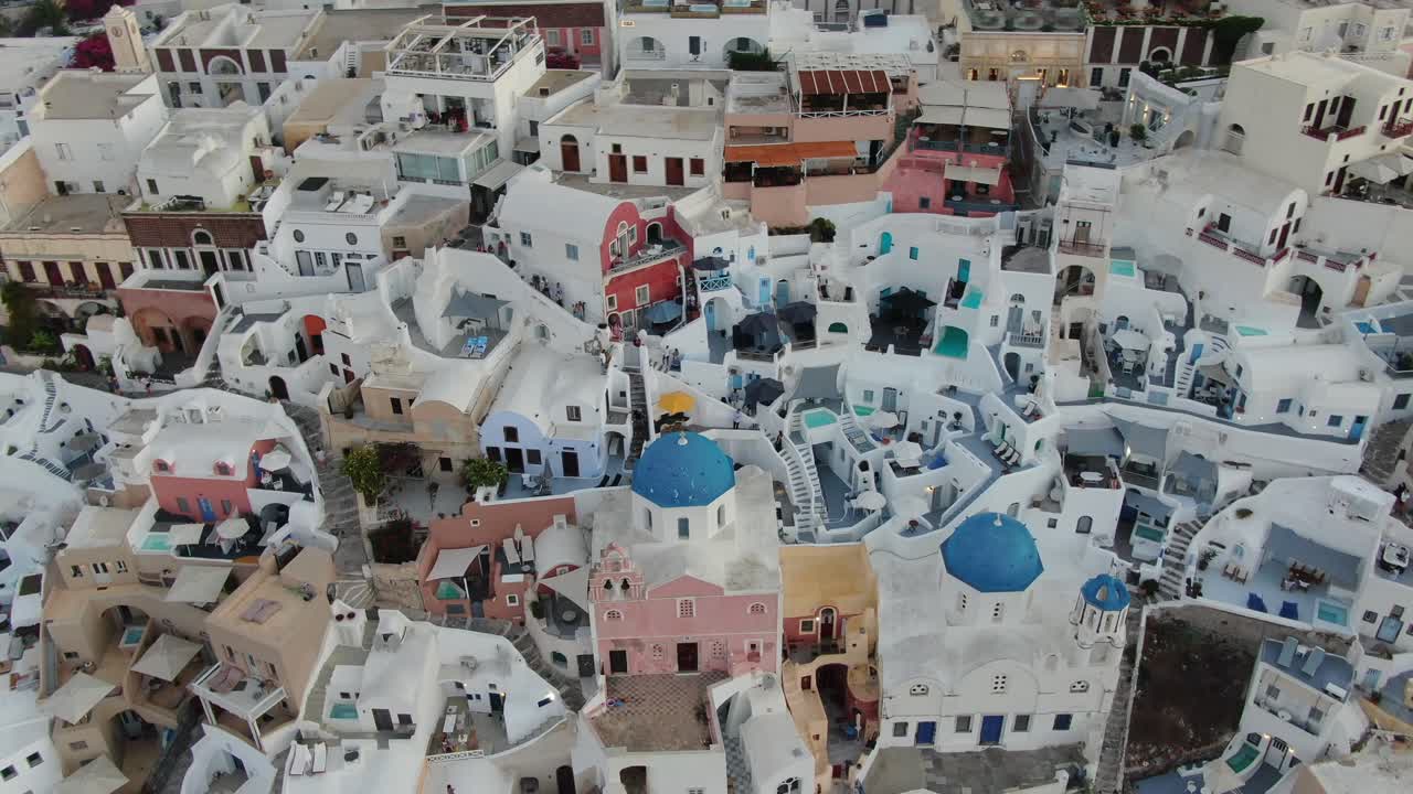 vista de avión no tripulado en grecia volando sobre santorini con la ciudad de oia casas blancas de cerca con frentes de colores y piscinas al amanecer