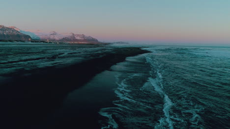 diamond beach striking black sand and glowing sunset across icelandic ocean waves, aerial view