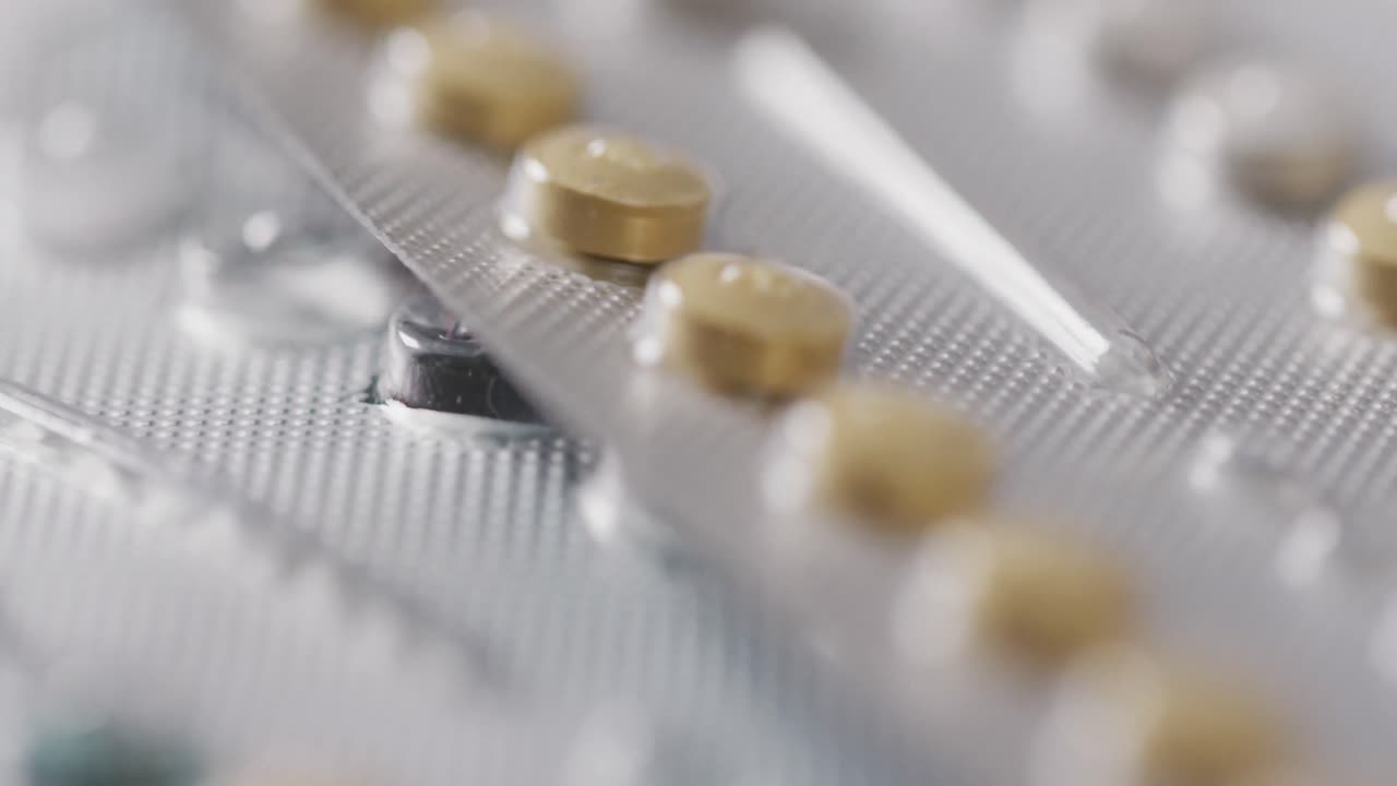 Video of close up of yellow tablets on pink background