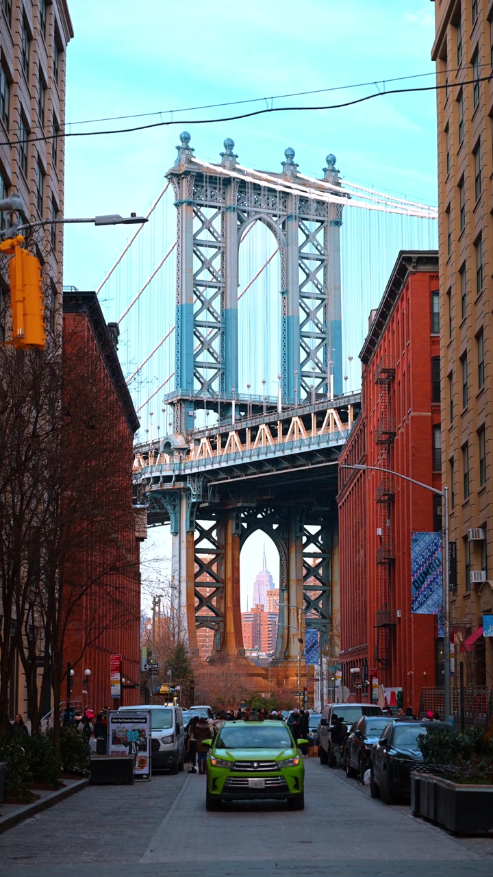 New York, USA, 12 gennaio 2026: Ponte di Manhattan incorniciato dal paesaggio urbano di DUMBO. Edifici in mattoni rossi fiancheggiano la strada mentre l'Empire State Building appare sotto l'arco d'acciaio