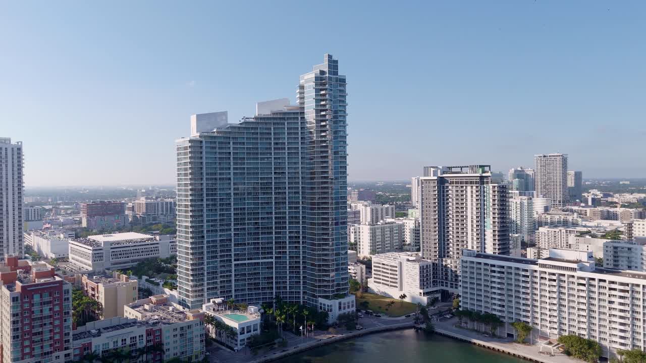 Aerial drone view of Miami waterfront high-rises in a sunny urban skyline, featuring modern architecture and turquoise water in the vibrant cityscape.