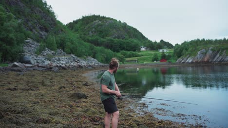 bearded caucasian guy with a rod fishing on a pond