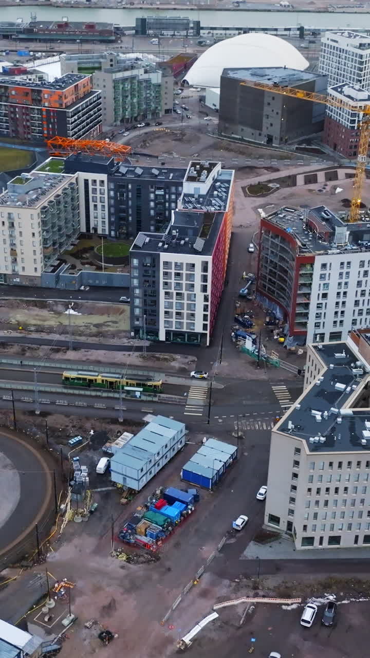 Vertical drone shot rotating over construction in Jatkasaari, in cloudy Helsinki