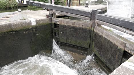 Canal-Pound-lock-chamber's-wooden-gates-letting-water-in-to-raise-narrowboat-inside