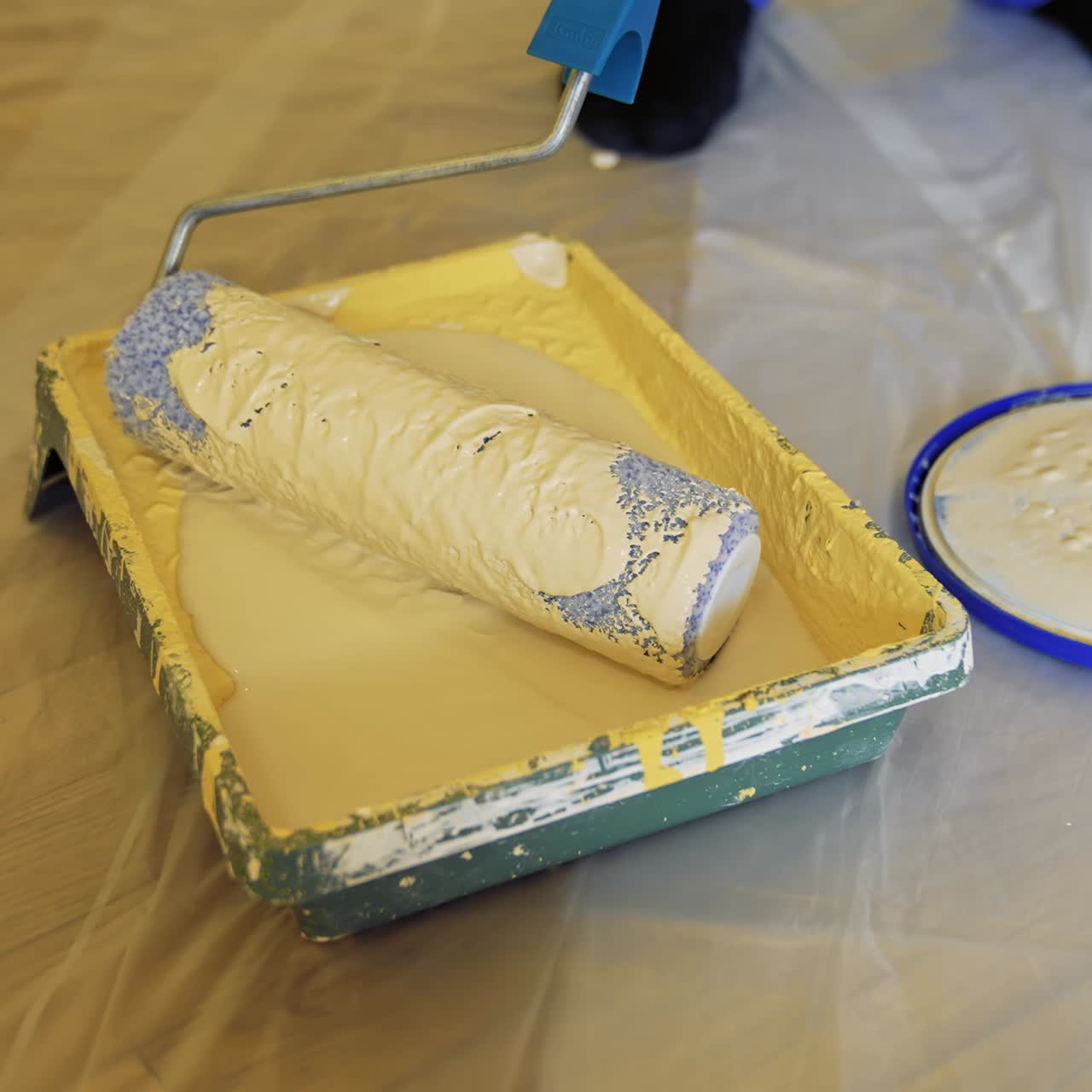 Paint tray with a roller. Worker is typing creamy color on a paint roller before painting walls. Dye in paint tray. Close-up