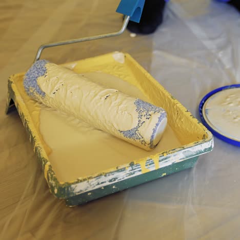 paint tray with a roller. worker is typing creamy color on a paint roller before painting walls. dye in paint tray. close-up