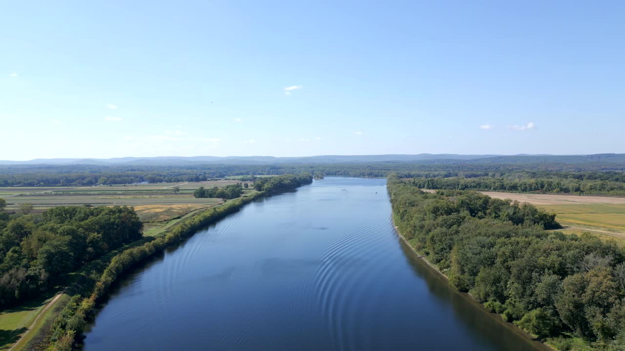 Aerial wide Connecticut River with forested banks stretching into the greenery environment, Hadley, Massachusetts, USA