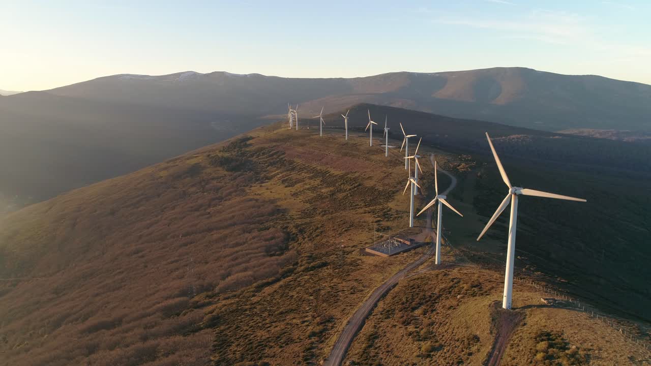 Windmills at the top of a mountain in the sunset aerial shot