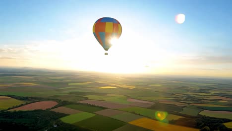 hot air balloon flying over farmland at sunset