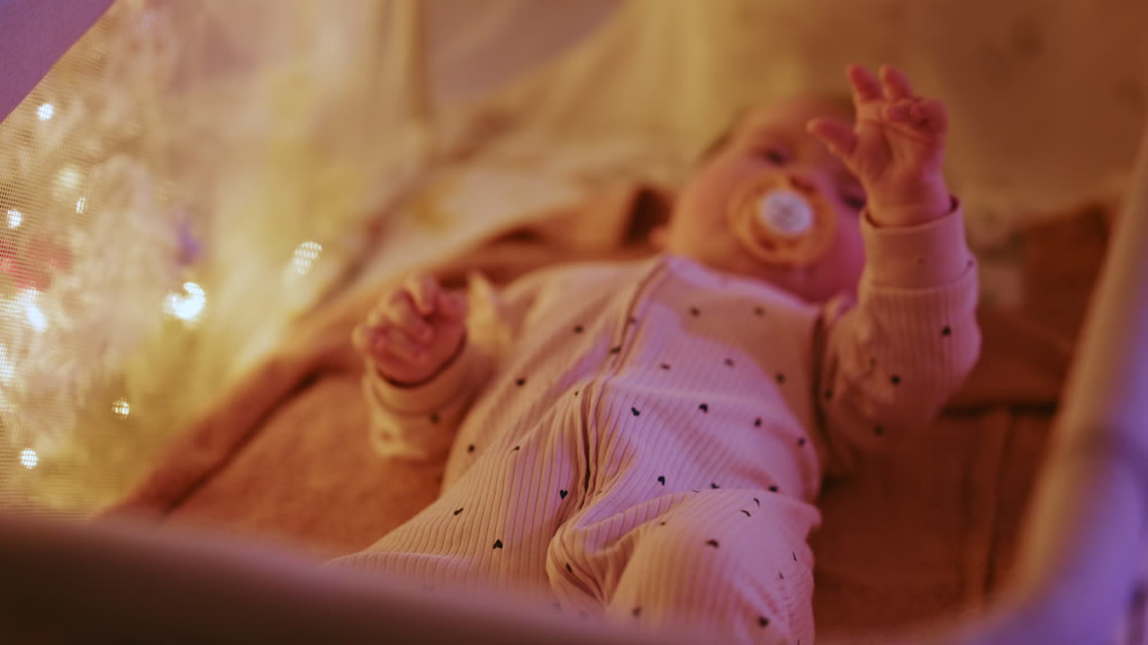 Primo piano di un bambino con un ciuccio illuminato da calde luci natalizie, che crea un’atmosfera festosa e toccante
