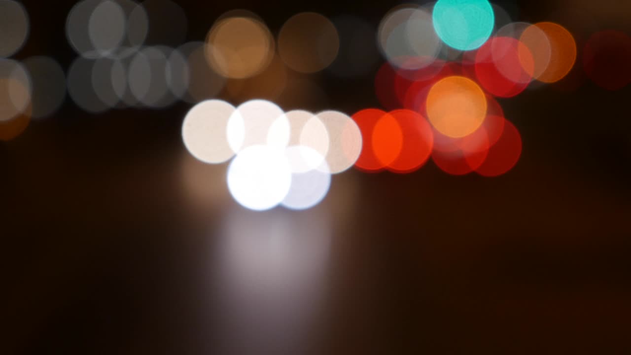 hermoso bokeh brillante en el fondo oscuro borroso por la noche. el redondo bokeh colorido brilla de las luces de los coches en la calle de la ciudad. fuera de foco con borroso. luces de la ciudad sin enfoque. bokeh de tráfico. concepto abstracto