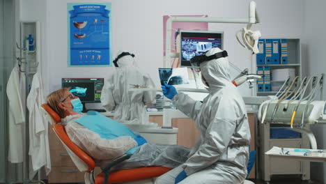 trabajador odontológico en kit de protección personal examinando radiografía dental