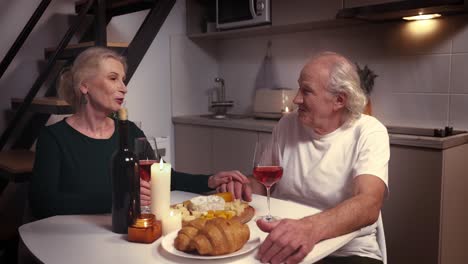 una pareja de ancianos disfrutando de una cena romántica en casa.