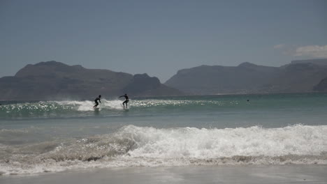 cámara lenta de surfistas a lo largo de la costa en sudáfrica