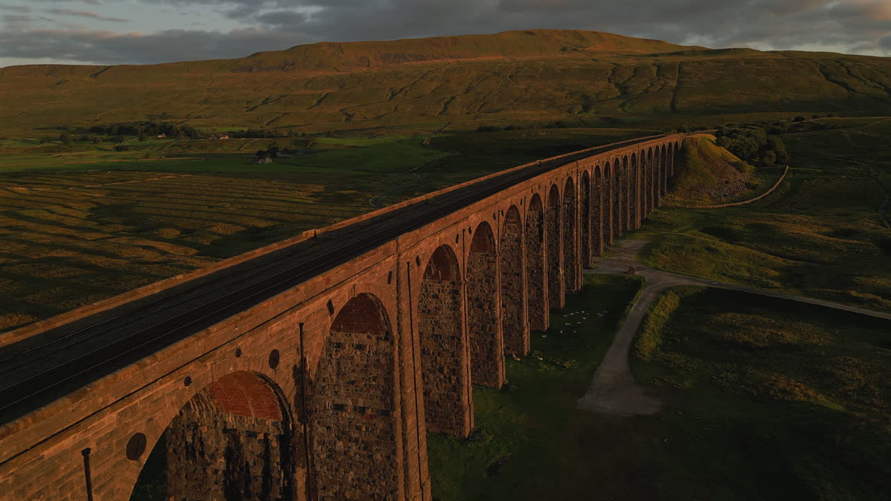 un drone de primer plano volando junto al viaducto de ribblehead en la hora dorada con whernside en el fondo