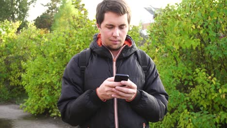 hombre enviando mensajes de texto por teléfono al aire libre