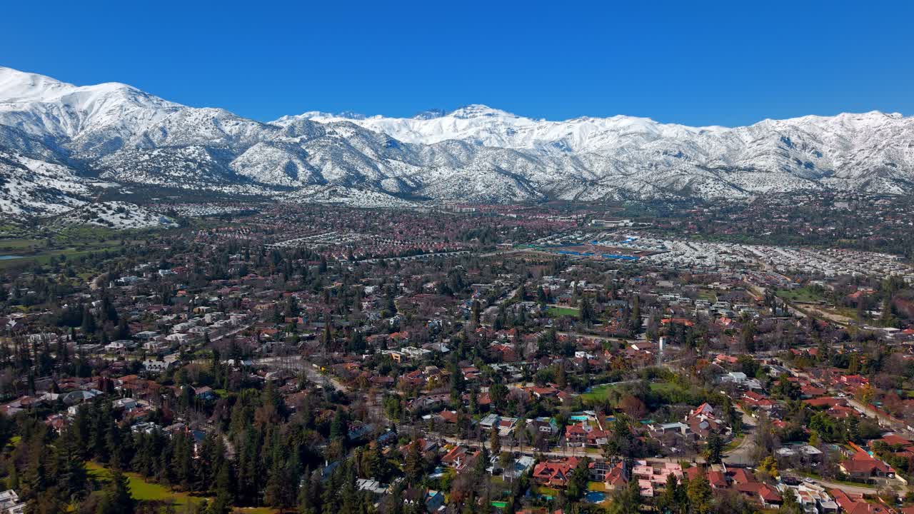 Ripresa aerea dolly in avanti sopra il quartiere urbano di Santiago, verso le Ande innevate