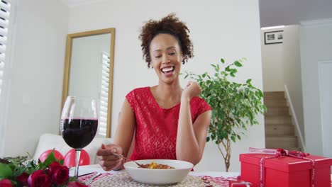 Mixed-race-woman-on-a-valentines-date-video-call,-drinking-wine