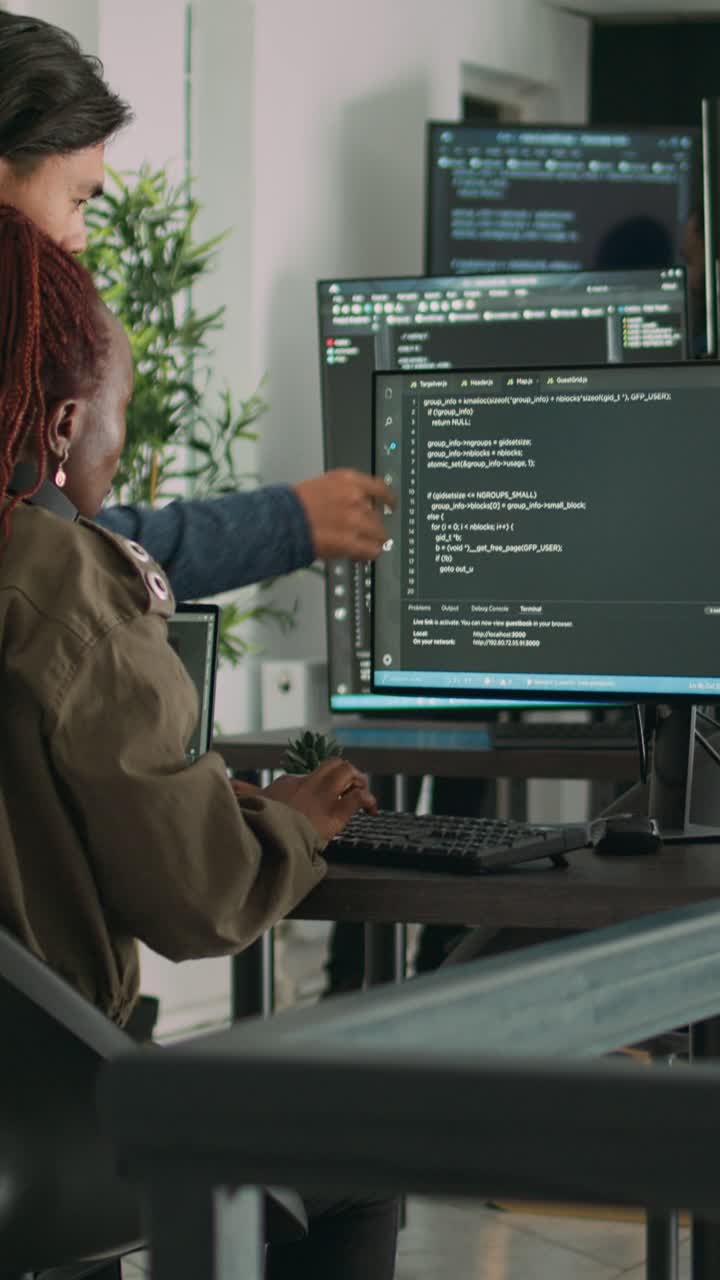 Vertical video: Diverse team of ai cloud programers talking about coding script in front of computer
