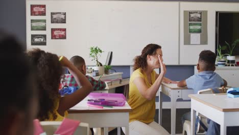 video of happy caucasian female teacher clapping hands with african american boy during lessons