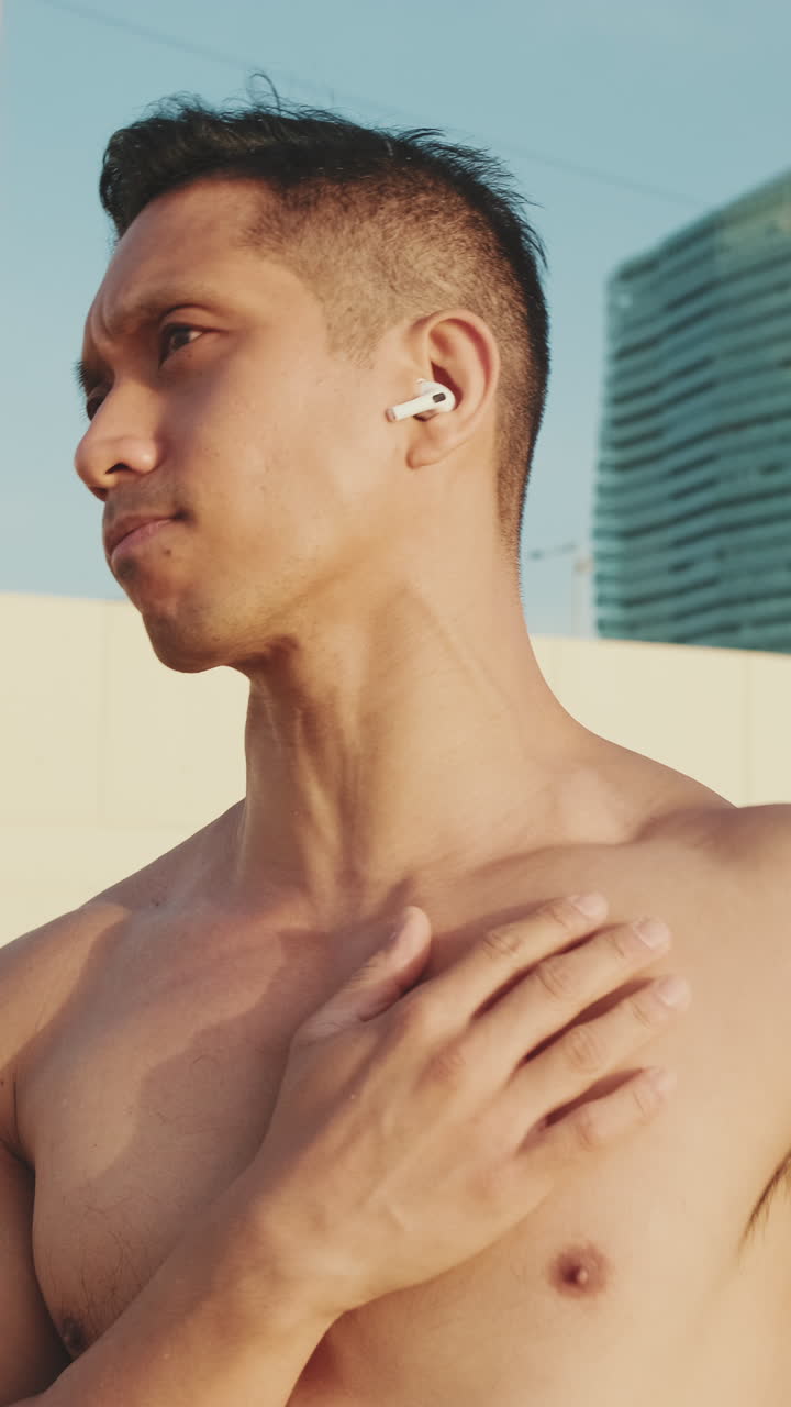 Uomo senza maglietta con auricolari sulla spiaggia