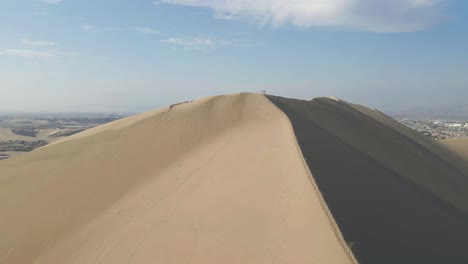 el dron asciende a las dunas de ica, revelando el impresionante panorama más allá del pico.