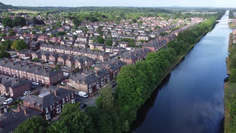 Aerial-view-flying-above-wealthy-Cheshire-housing-estate-alongside-Manchester-ship-canal-slow-descending-shot