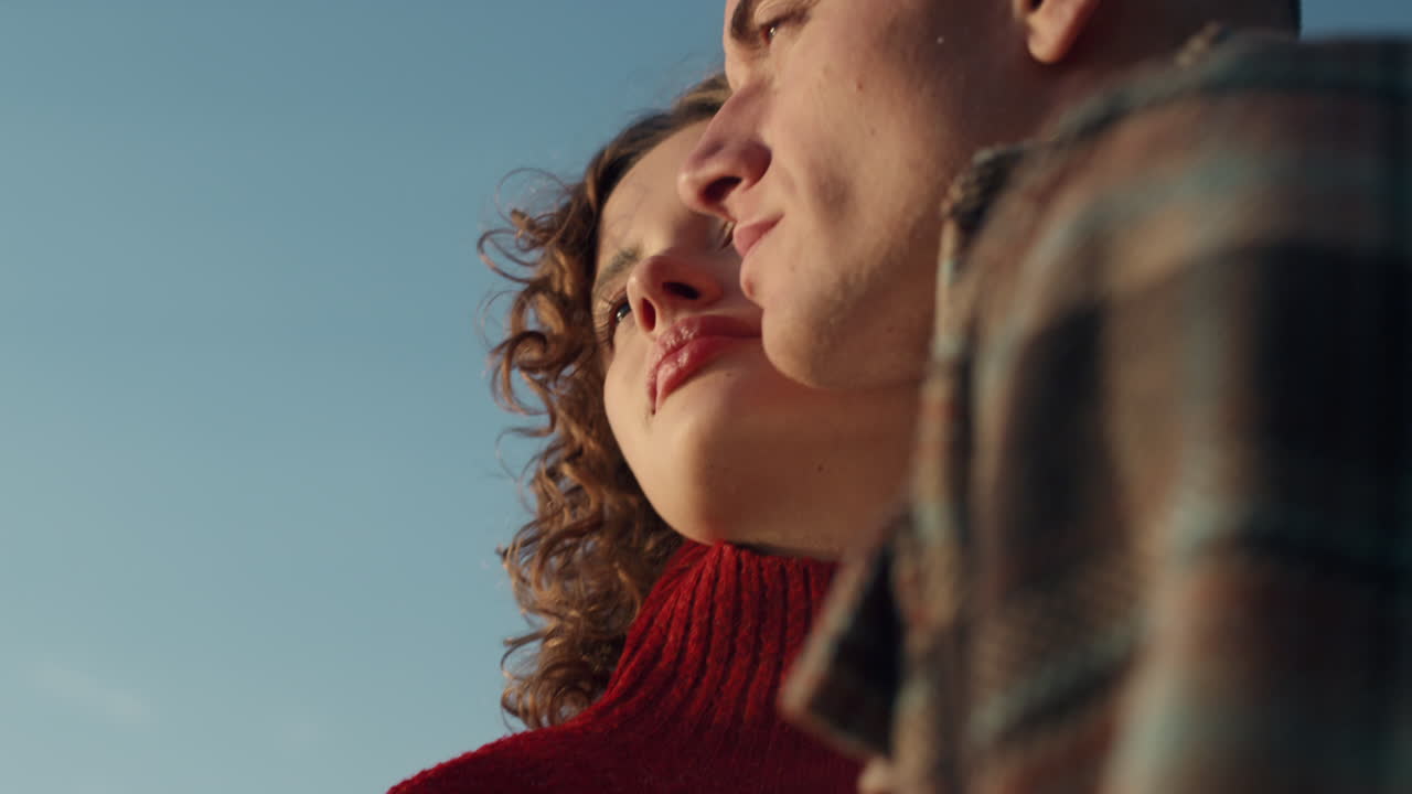 Romantic couple standing on beach. Happy woman and man posing at camera