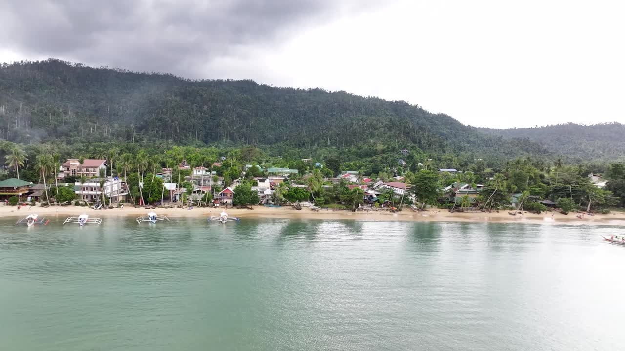 Sandy tropical beach with small boats, drone pull back reveal seascape in Port Barton, Palawan