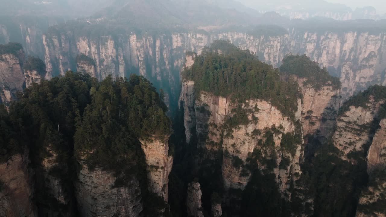 Aerial panorama of dense forest atop massive sandstone formations in Zhangjiajie National Park surrounded by deep cliffs and valleys