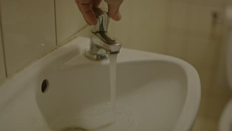 man turning on faucet and washing hands with soap in old and dirty bathroom