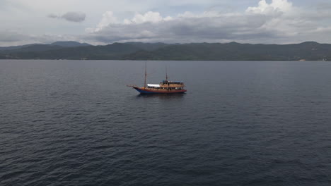 Barco-De-Madera-Navegando-En-Un-Mar-En-Calma-Con-Un-Cielo-Sombrío-En-Bali,-Indonesia